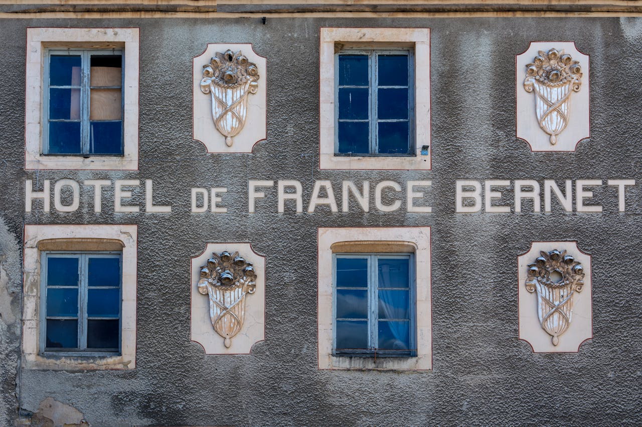 Close-up of Hotel de France Bernet facade in Saint-Saulge, showcasing vintage windows and ornate design elements.