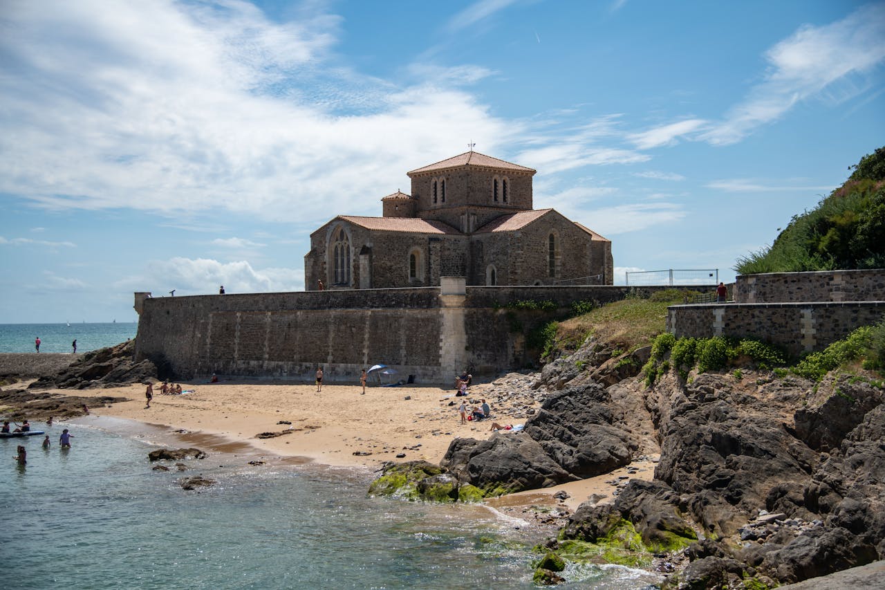 team-03 Scenic view of Prieure Saint-Nicolas church by the beach in France, under a blue sky.