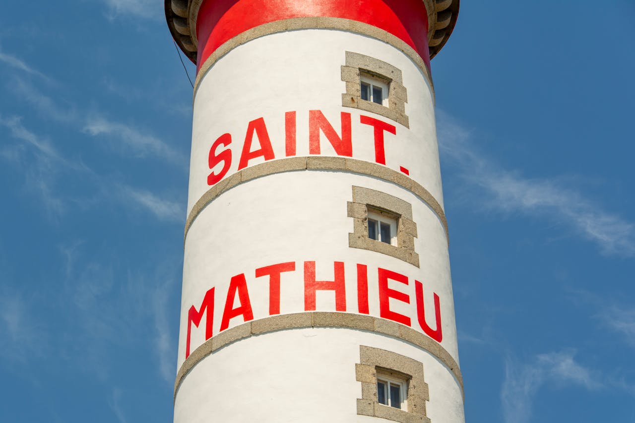 Close-up of Saint Mathieu Lighthouse with blue sky background, showcasing bold red text.